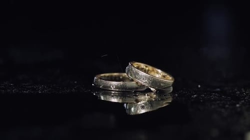 Wedding Rings on Dark Water Surface Shining with Light
