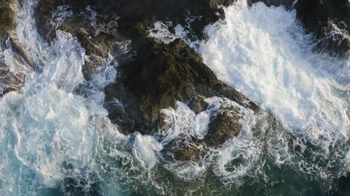 Aerial drone view of Sea waves crashing into rocks. Flying above ocean coast