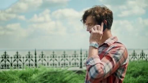 Homme avec smartphone debout sur un chemin dans un parc. Guy appelle un téléphone portable à l'extérieur