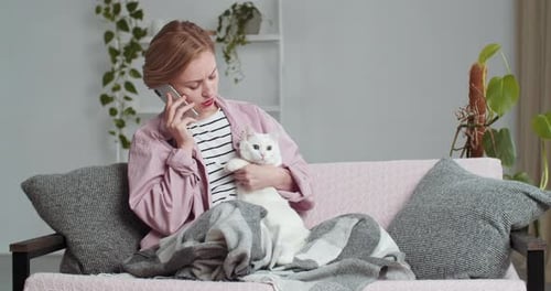 Une pigiste sérieuse et concentrée est assise sur le canapé du salon recouverte d'une couverture en laine douce