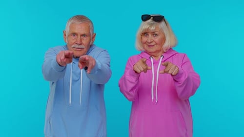 Ältere Oma mit Großvater, der auf die Kamera zeigt, schaut mit glücklichem Ausdruck und trifft Wahl