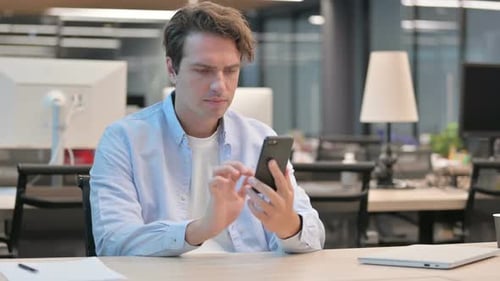 Attraktiver Mann nutzt Smartphone im Büro