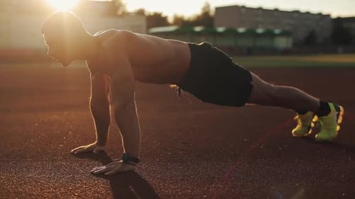 Fit Man Doing Pushups at Track at Sunrise