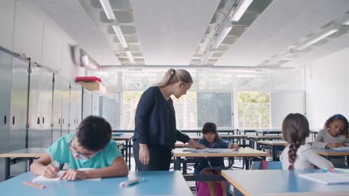 Female School Teacher Walking Between Desks