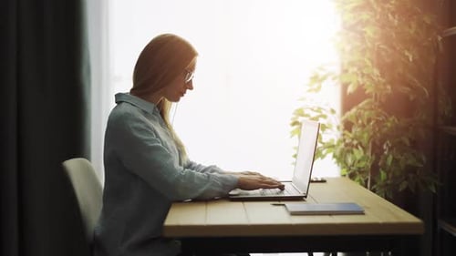 Woman Works on Laptop at Sunny Home Office