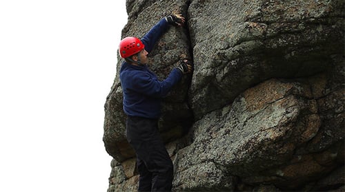 Man Climbing a Rocky Cliff Face Outdoors