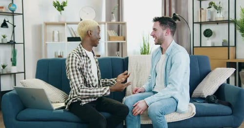 Two Young Adults Embrace on a Couch Indoors