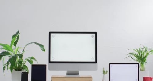 Video of laptop, smartphone, tablet and computer on wooden table with copy space in office