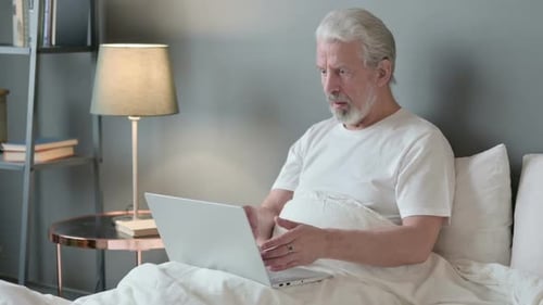 Senior Man Using Laptop in Bed is Confused