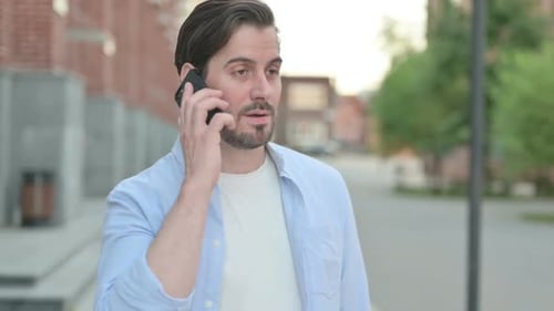 Young Adult Man Talking on Phone Outside