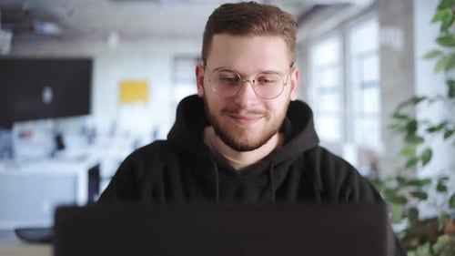 Young Man Working on Laptop in Modern Office