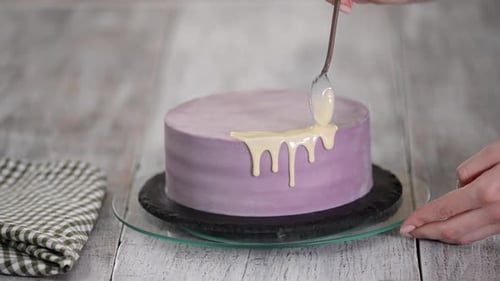 Preparation of a holiday cake. The girl pours liquid white chocolate.
