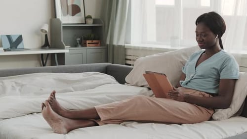 Woman on Bed Using Tablet Device Indoors