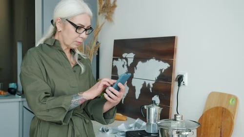 Woman Using Phone in Modern Kitchen