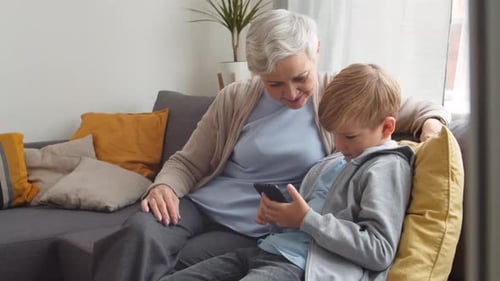 Grandmother and Grandson Relaxing at Home Using Smartphone