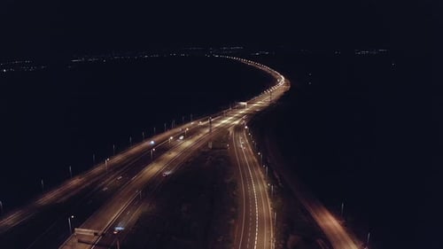 Drohnenluftaufnahme des Nachtverkehrs auf einer Autobahn, die Autos und Lichtspuren mit Brücken zeigt
