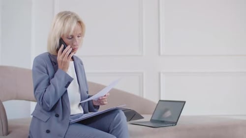Female Manager Discussing Documents by Cellphone