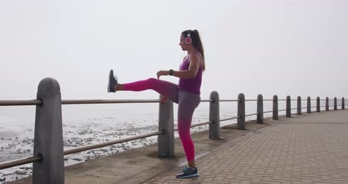 Woman Stretching Leg on Railing Next to Ocean