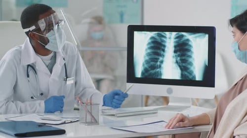 Doctor Explains X-Ray to Patient with Protective Mask