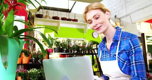 Smiling florist using laptop in flower shop
