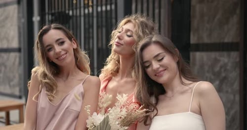 Three Hapy Ladies with Bouquets Posing in the City
