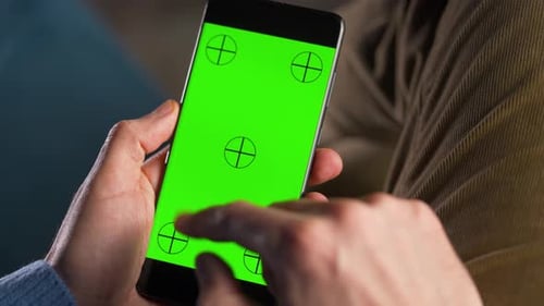 Man Using Smartphone with Green Mockup Screen in Vertical Mode