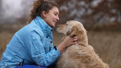Woman and Golden Retriever Cuddle in Nature