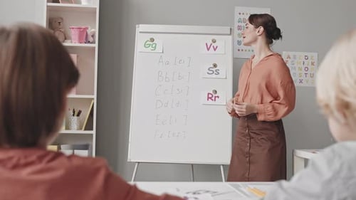 Teacher Explains Letters to Children in Classroom