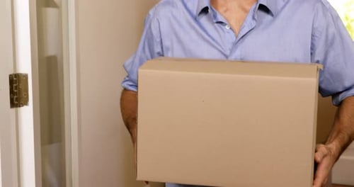 Man Smiles Carrying Box Into New Home