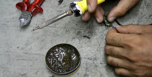 Adult Soldering Wires onto Circuit Board Close Up