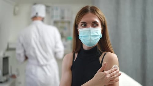 Positive Young Woman Gesturing Thumb Up After Vaccination in Clinic Indoors