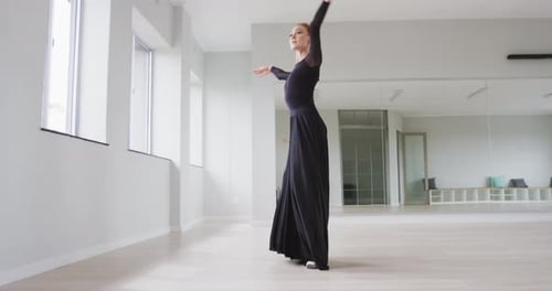Caucasian female ballet dancer practicing ballet during a dance class in a bright studio