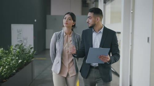 Young Arab Businessman Walking with Woman Investor Along Office and Showing Her Corporate