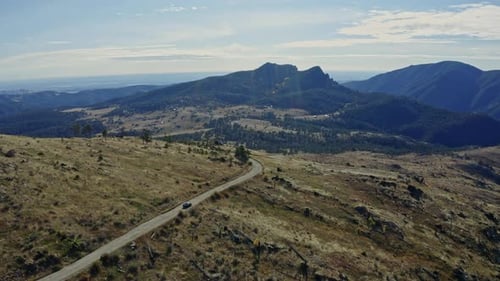 Aerial following car down remote mountain dirt road in day time, 4K