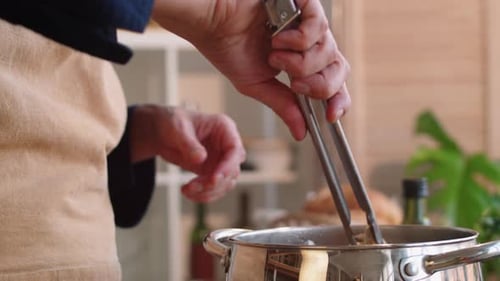 Close Up of Man Using Tongs while Cooking Spaghetti