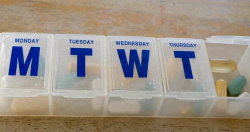 Close up on a medical prescription pill box organizer full of vitamins and health supplements with a