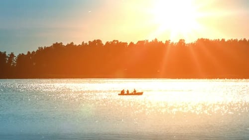 People Rowing Boat on Lake at Sunrise