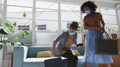 Two woman wearing face masks sitting on a couch at office
