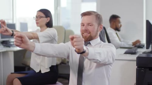 Office Workers Doing Arm Stretches at Desks