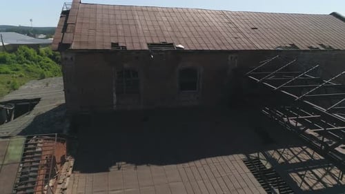 Aerial view of old red brick factory with an iron roof next to the river 32