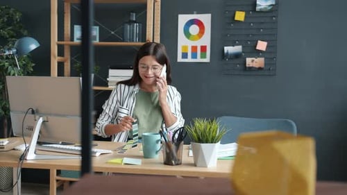 Young Woman Talking on Phone Working at Desk