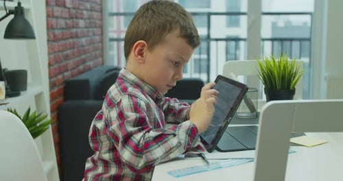 Boy Using Tablet Device at Table Indoors