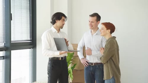 Confident Caucasian Real Estate Agent with House Model on Laptop is Talking to Clients About Buying