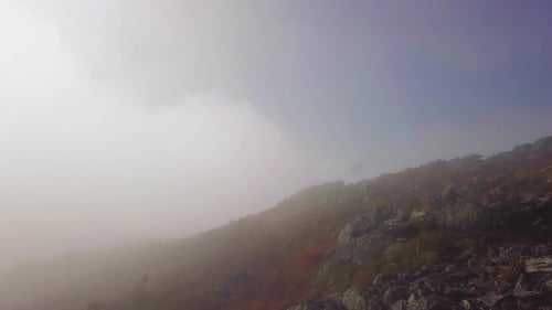 Stone Run on Mountain Surrounded with Clouds and Fog. Aerial View From Drone of Loose Rocks on Hill