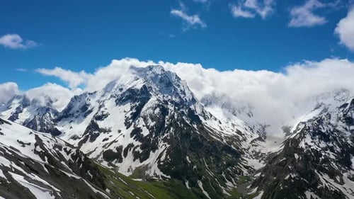 Air Flight Through Mountain Clouds Over Beautiful Snowcapped Peaks of Mountains and Glaciers