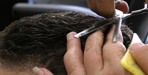 Barber Cutting Dark Wavy Hair with Scissors