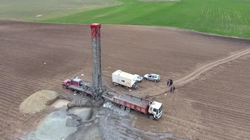 Bohranlage arbeitet auf flachem landwirtschaftlichem braunem Feld