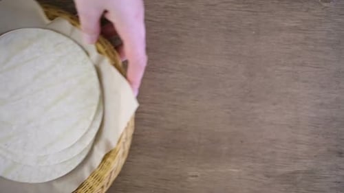 Fresh white corn tortillas on a wood background.