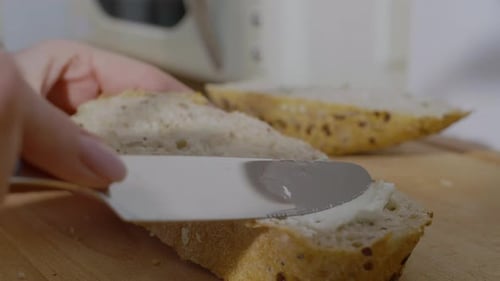 Woman Spreads Cream Cheese on Whole-Grain Bread