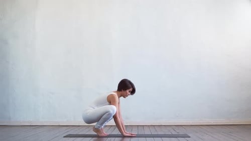 Young Woman Demonstrates Crow Yoga Pose in Studio